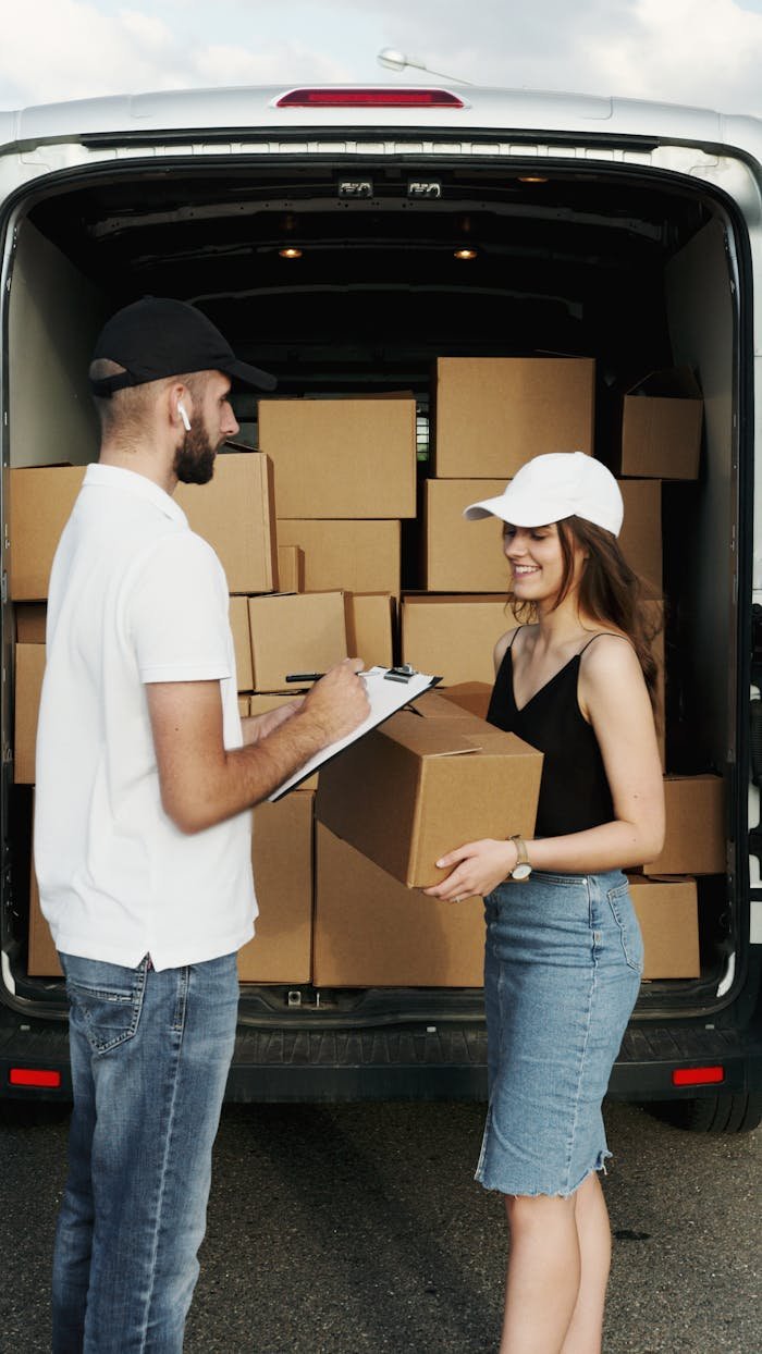 about-us A delivery person hands a package to a woman from a van full of parcels outdoors.